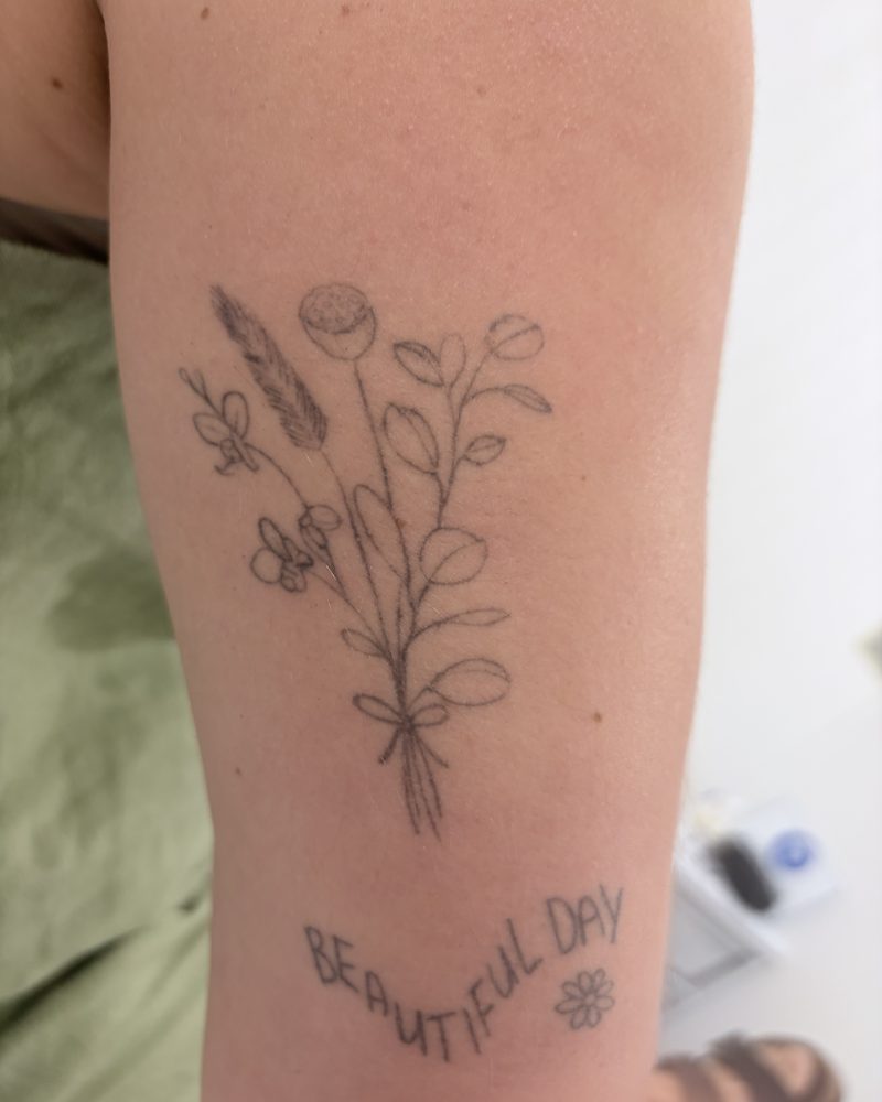 Fine line floral tattoo on a forearm before treatment